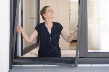 Frau bei der Anbringung eines Insektenschutzgitter Fenster