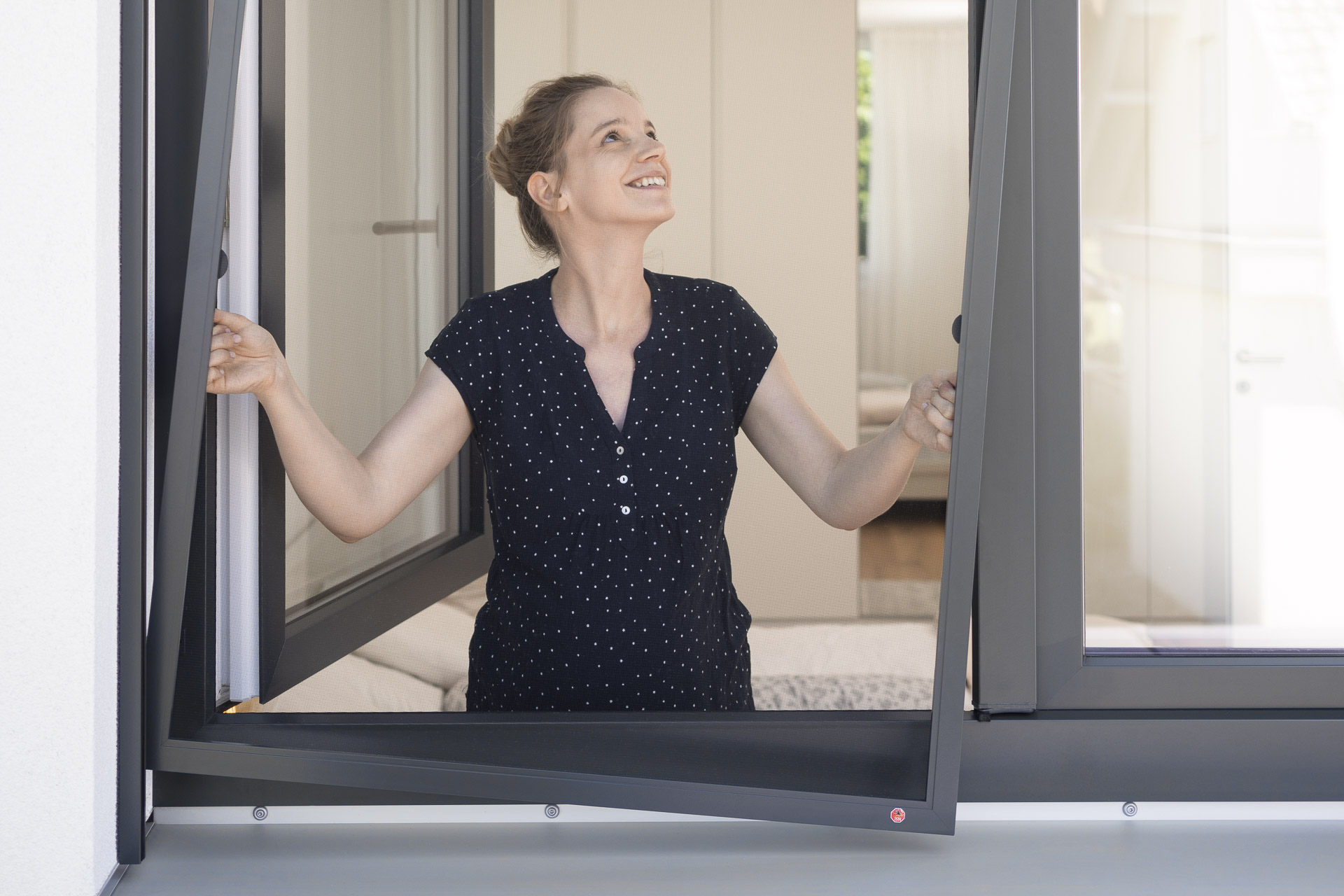 Frau bei der Anbringung eines Insektenschutzgitter Fenster